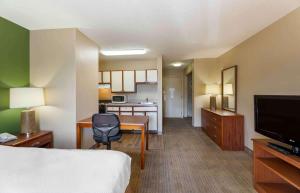 a hotel room with a bed and a desk and a kitchen at Suburban Studios Copley Akron West in Copley