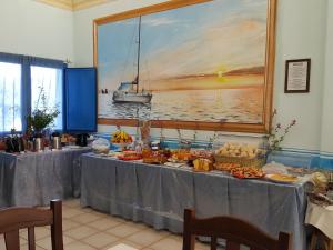 a table with food and a painting of a boat at Hotel Baia Cea in Bari Sardo