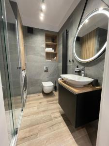 ein Badezimmer mit einem Waschbecken, einem WC und einem Spiegel in der Unterkunft Stylowy Apartament - Port Mielno in Mielno
