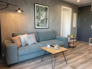 een woonkamer met een blauwe bank en een tafel bij Stylowy Apartament - Port Mielno in Mielno