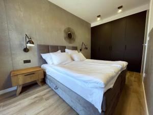 ein Schlafzimmer mit einem großen Bett und einem Nachttisch in der Unterkunft Stylowy Apartament - Port Mielno in Mielno