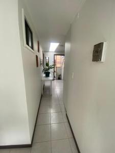 a hallway with a white wall and a white tile floor at Hostal Florecer in Angol
