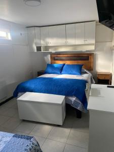 um quarto com uma cama azul e um armário branco em Hostal Florecer em Angol