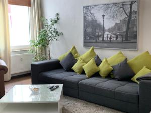 uma sala de estar com um sofá com almofadas amarelas e azuis em TOP-Zentrum Fußgängerzone, 81 qm, Küche, Parkplatz em Oldenburg