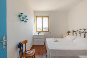 a bedroom with a bed and a window and a chair at BED BIANCANEVE Attico in Villanova di Ostuni