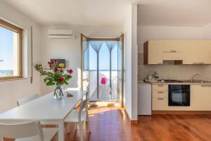 a kitchen and dining room with a table with a vase of flowers at BED BIANCANEVE Attico in Villanova di Ostuni