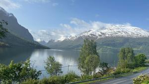 a road next to a lake with a snow covered mountain at Solvik #apartment #Loen in Loen