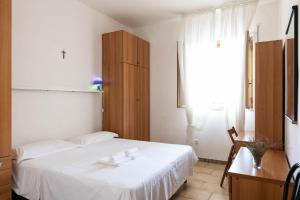 a bedroom with a white bed and a wooden cabinet at BED BIANCANEVE Miniappartamento in Villanova di Ostuni