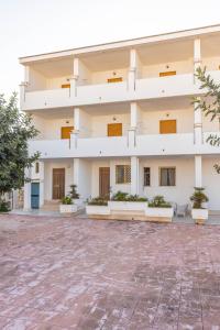 a large white building with potted plants in the courtyard at BED BIANCANEVE Miniappartamento in Villanova di Ostuni
