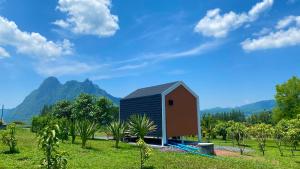 una casa in un campo con montagne sullo sfondo di ไร่วิวทิวเขา ลานกางเต็นท์ ฟาร์มสเตย์ a Ban Nong Tum