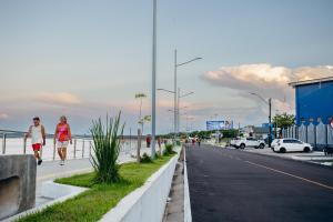 two people walking down a street next to the beach at Hotel Filhos da Promessa in Tucuruí