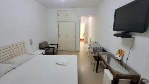 a bedroom with a white bed and a flat screen tv at Apto Cavalinho Branco in Águas de Lindoia