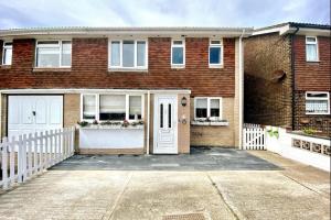 a brick house with white doors and a white fence at 1min walk to Beach- Happy Waves- Family Home in Camber