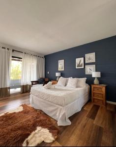 a bedroom with a large bed and a blue wall at La Bonita Suites Punta Colorada in Punta Colorada