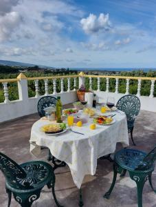 a table with plates of food and drinks on a balcony at Quinta do Sossego-Giestas in Ribeira Grande