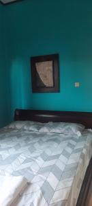 een bed in een kamer met een blauwe muur bij Raja Grya in Tirtagangga