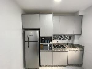 a kitchen with white cabinets and a stainless steel refrigerator at SPAZIO LA VITTA LONDRINA in Londrina
