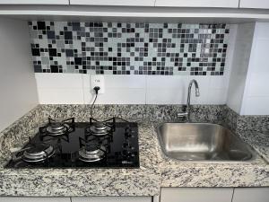 um balcão de cozinha com um fogão e um lavatório em SPAZIO LA VITTA LONDRINA em Londrina