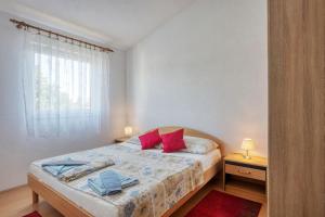 Un dormitorio con una cama con almohadas rojas y una ventana en Apartments with a parking space Zablace, Sibenik - 4219, en Zablaće