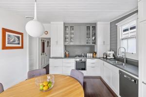 uma cozinha com armários brancos e uma mesa de madeira em COOK3R - Character on Cook Street em Sydney
