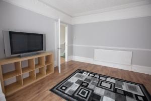 a living room with a flat screen tv and a rug at Beach palace in Clacton-on-Sea