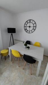 Biały stół i krzesła z zegarem na ścianie w obiekcie Apartamento en Foz. Primera Línea Playa Rapadoira w mieście Foz +29 zdjęć
