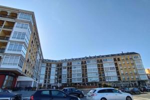 duży budynek z samochodami zaparkowanymi na parkingu w obiekcie Apartamento en Foz. Primera Línea Playa Rapadoira w mieście Foz