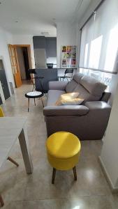 salon z kanapą i żółtym stołkiem w obiekcie Apartamento en Foz. Primera Línea Playa Rapadoira w mieście Foz