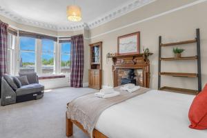 a bedroom with a bed and a chair and a fireplace at Marchmont Traditional Apartments in Edinburgh