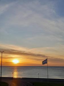 una puesta de sol sobre el océano con una bandera en un camino en Marmol y Constitución, con vista al mar en Mar del Plata