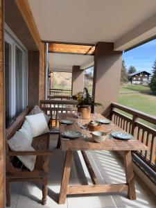 a wooden table and bench on a balcony with a table and chairs at Le nid douillet de l’ecureuil in Péone