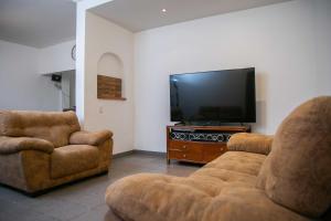 a living room with two chairs and a flat screen tv at Casa Lili in Oaxaca City