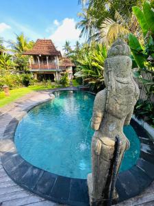 uma estátua em pé em frente a uma piscina em Puri Sundaram Villa em Ubud