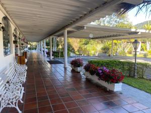 una pasarela cubierta con bancos blancos y flores en Hotel Cavalinho Branco, en Águas de Lindóia