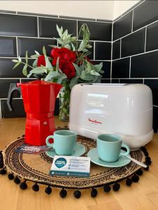 una mesa con dos tazas y una tostadora y flores en Rural Norte, en Bañugues