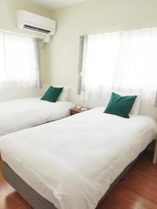 two beds in a room with white sheets and green pillows at Fortuna YAKA in Kin