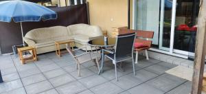 a patio with a table and chairs and a couch at Ebenerdig mit Terrasse & Garten, WLAN & Parkplatz! Self Check-in & Check-out! Schwedenofen! in Auggen
