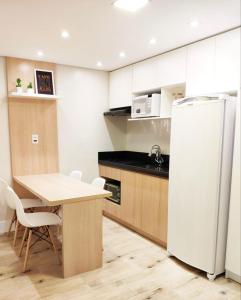 a kitchen with a white refrigerator and a table at 20º Andar Vista Linda Próx a Santa Casa, UFRGS - BnB Serviços Inteligentes Por Fioravante in Porto Alegre