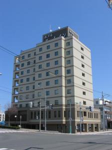 Un grand bâtiment blanc avec un panneau en haut dans l'établissement Hotel Route-Inn Abashiri Ekimae, à Abashiri