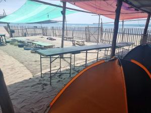 un grupo de mesas de picnic en la playa en Villa violeta beach resort en San Juan