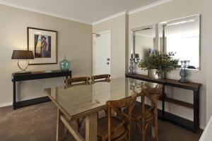 StayCentral - Cityside on Whiteman Street Southbank في ملبورن: غرفة طعام مع طاولة زجاجية وكرسيين