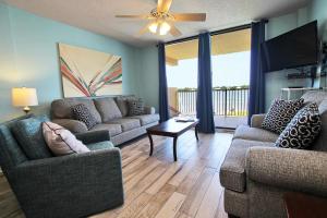 sala de estar con 2 sofás y TV de pantalla plana en Compass Point 205 en Gulf Shores