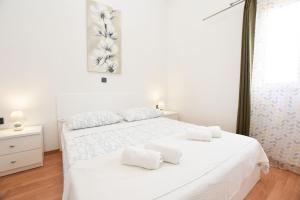 a white bedroom with a white bed with two white towels at Apartments Zorana in Rogoznica