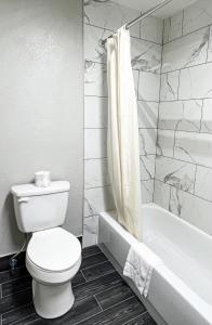 a bathroom with a toilet and a tub and a sink at Regency Inn Bald Knob in Bald Knob