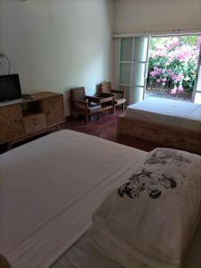 a bedroom with two beds and a tv and a window at Nirwana Sea Side Cottages in Lovina