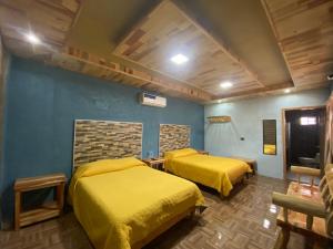 twee bedden in een kamer met gele lakens bij Cabañas Rochivo Ranch in Creel