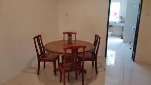 a wooden table with four chairs and a kitchen at Cozzy26 Homestay in Bintulu