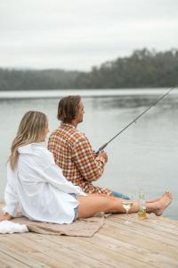 un homme et une femme assis sur un quai de pêche dans l'établissement The Leaning Oak Holiday Lifestyles - Lake Conjola, à Conjola