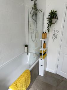 y baño con ducha y bañera amarilla. en Ty Pentref - Cwmcarn Village House en Cwmcarn