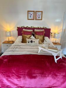 a bedroom with a large pink bed with two lamps at Ty Pentref - Cwmcarn Village House in Cwmcarn